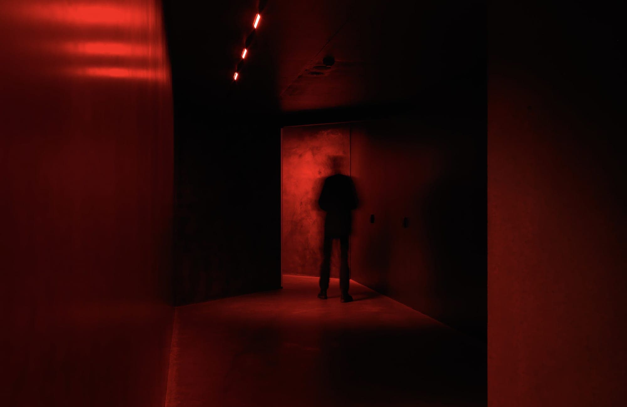 A dark silhouette in a red lit hallway